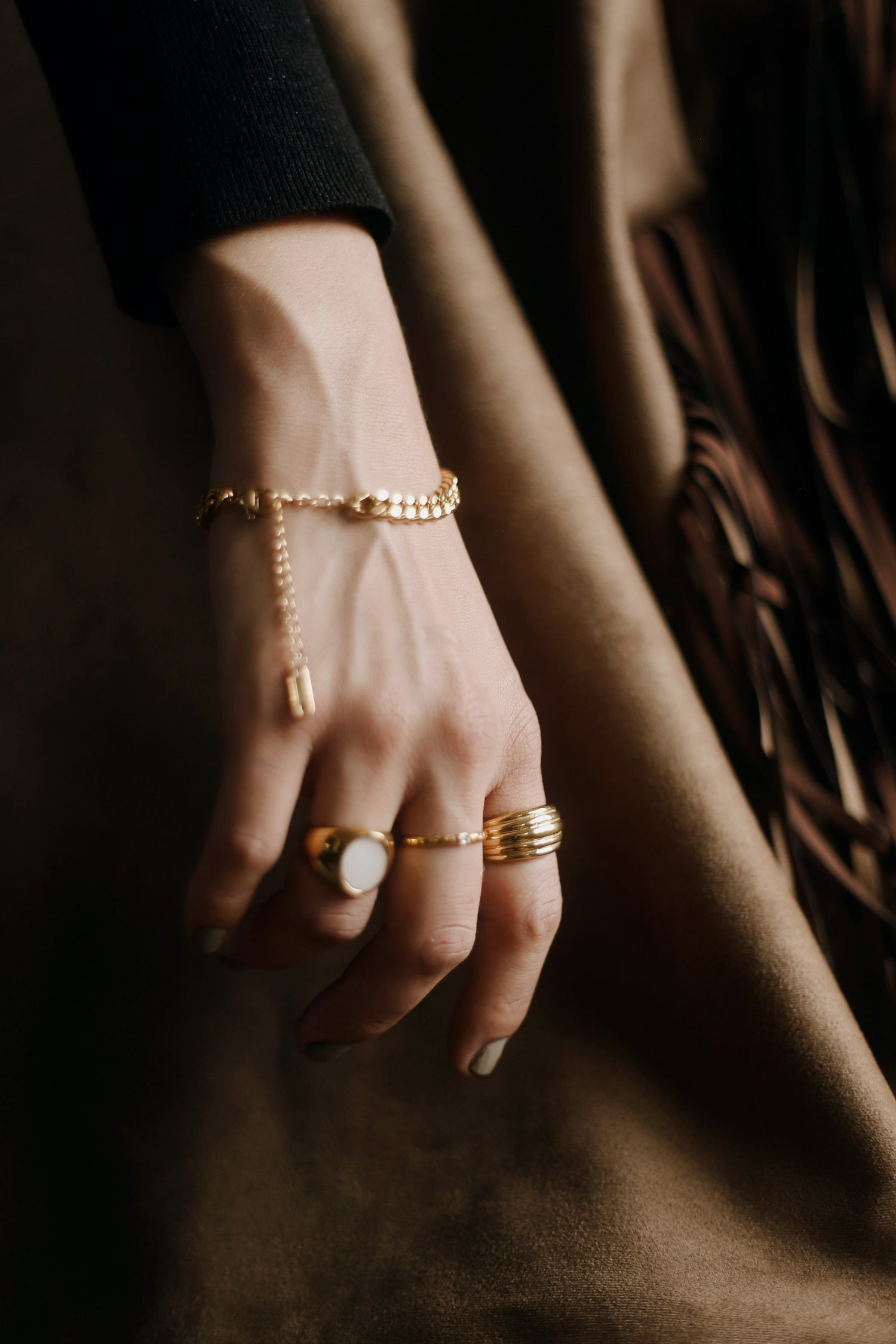 Hand wearing ETCH gold rings and bracelet